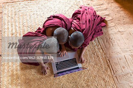 Myanmar, Mandalay division, Bagan. Three novice monks using a laptop in a pagoda, shot from above (MR)