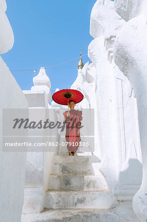 Myanmar, Mandalay division, Mingun. Novice monk with red umbrella standing on Hsinbyume Pagoda (MR)