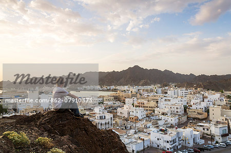Oman, Muscat. Tourist looking at Mutrah old town, elevated view, at sunrise (MR)