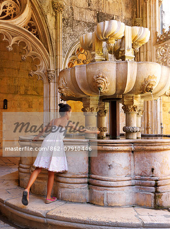 Portugal, Estremadura, Batalha, Monastery of Santa Maria da Vitoria, girl touching fountain (UNESCO World Heritage), (MR)