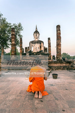 Thailand, Sukhothai Historical Park. Buddhist monk praying at Wat Mahathat temple at sunrise (MR)