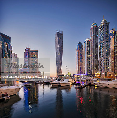 Dubai Marina at twilight with the Cayan Tower (Infinity Tower), the Dubai Marriott Harbour Hotel and Suites and various residential towers, Dubai Marina, Dubai, The United Arab Emirates.