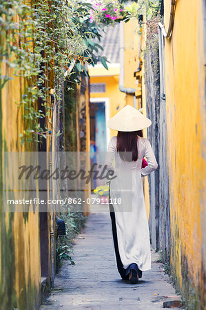 Vietnam, Hoi An. Young vietnamese girl with Ao Dai dress walking in a alley (MR)