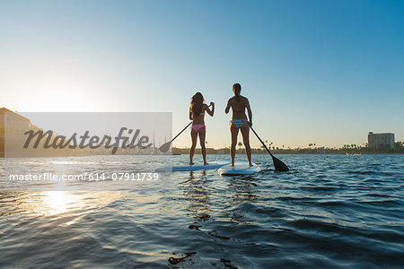 Rear view of two women stand up paddleboarding, Mission Bay, San Diego, California, USA