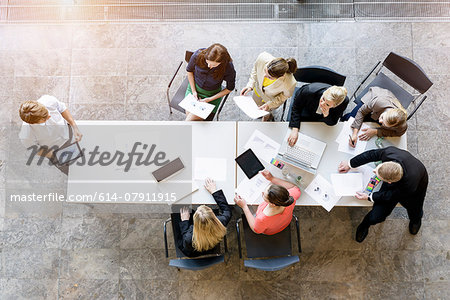 Overhead view of business team meeting at desk in office Overhead view of business team meeting at desk in office