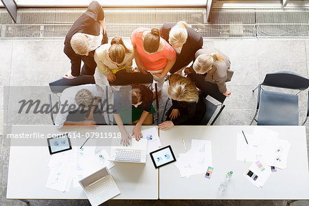 Overhead view of huddled business team meeting at desk in office