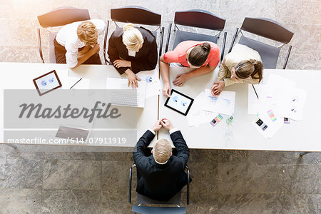 Overhead view of businessmen and women meeting client at desk in office