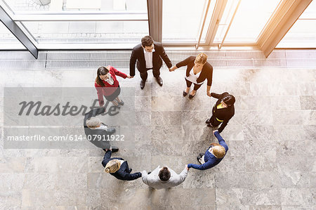 Overhead view of businessmen and women in circle holding hands Overhead view of businessmen and women in circle holding hands