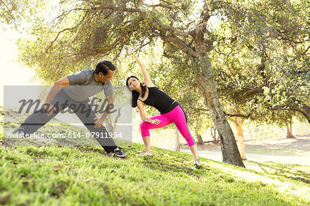 Mature running couple warming up together in park