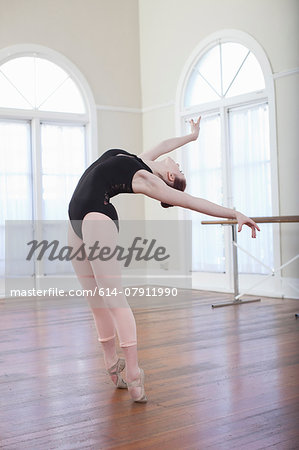 Teenage ballerina leaning back in ballet position at ballet school