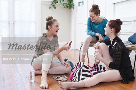 Three teenage girls chatting and laughing in ballet school