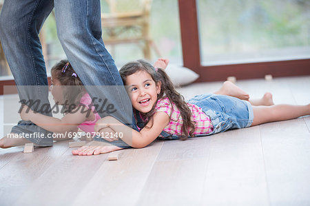 Low section of father dragging girls on hardwood floor