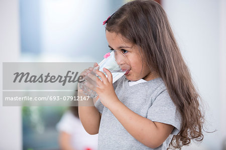 Cute girl drinking glass of water at home