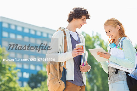 Male and female students using digital tablet at college campus