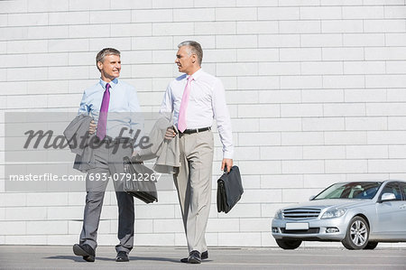 Full length of businessmen with briefcases walking on street