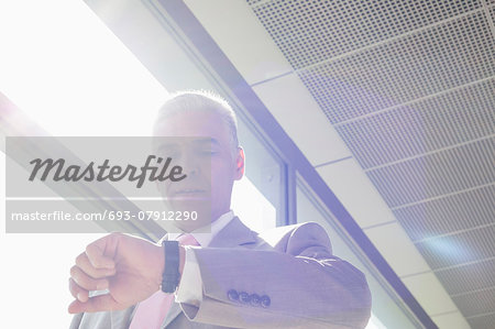 Middle aged businessman checking time at railroad station