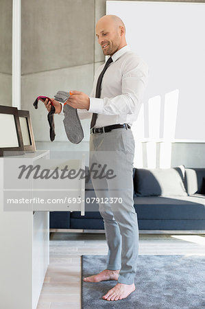 Full length side view of businessman selecting socks at home