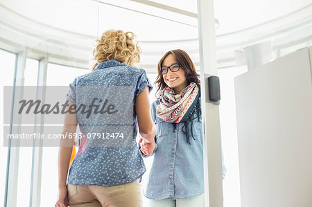 Happy businesswomen shaking hands in creative office