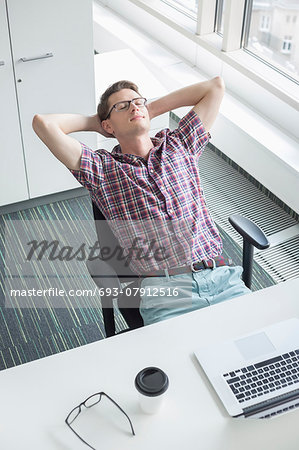 High angle view of businessman relaxing at desk in creative office