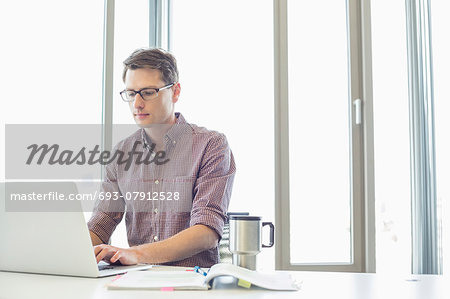 Businessman working on laptop at desk in creative office