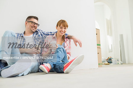 Full-length of cheerful couple with coffee cups in new house Full-length of cheerful couple with coffee cups in new house