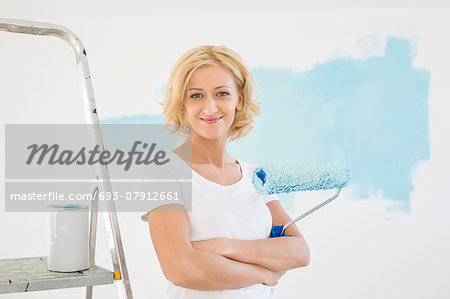 Portrait of woman with paint roller in new house