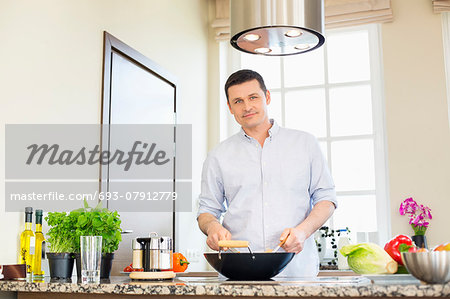 Portrait of confident man preparing food in kitchen