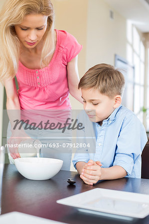 Mother pouring milk for son at table