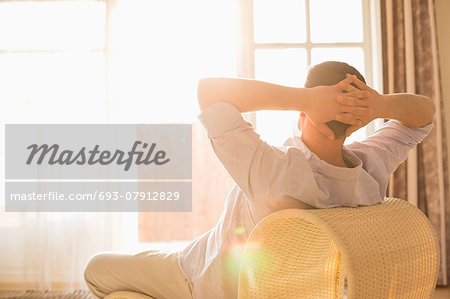 Rear view of man relaxing on chair at home
