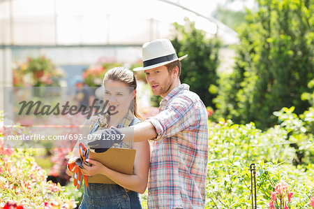 Male gardener discussing with supervisor outside greenhouse