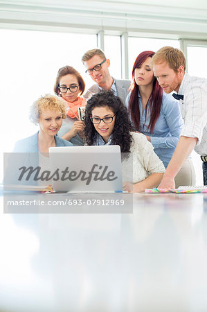 Business colleagues using laptop at desk in creative office Business colleagues using laptop at desk in creative office
