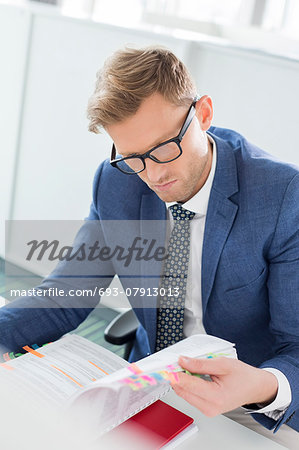 Businessman reading file at desk in creative office