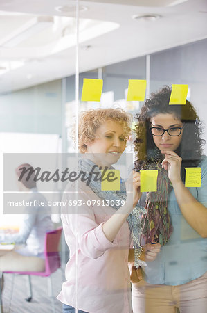 Businesswomen brainstorming with sticky notes in office