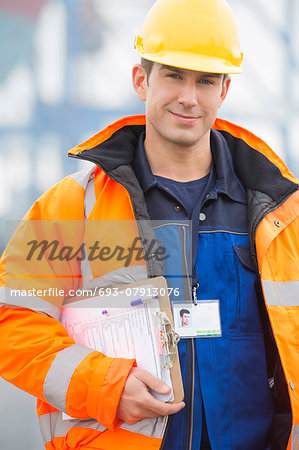 Portrait of confident mid adult man with clipboard in shipping yard