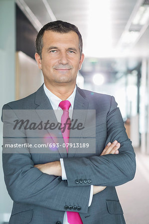 Portrait of middle-aged businessman standing with arms crossed in office Portrait of middle-aged businessman standing with arms crossed in office