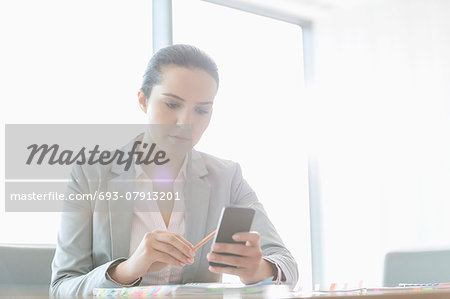 Young businesswoman using cell phone in office