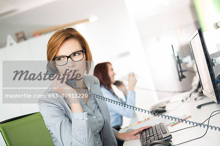 Young businesswoman talking on telephone at desk in office