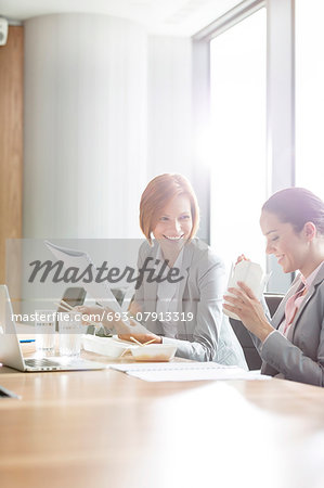 Young businesswomen having lunch at table in office