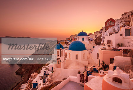 Greek church with three blue domes at sunset, Oia, Santorini (Thira), Cyclades Islands, Greek Islands, Greece, Europe