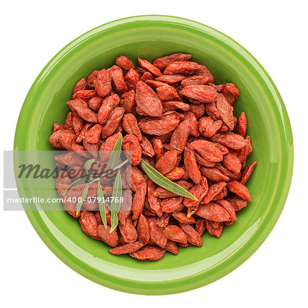 dried goji berries with a fresh leaf on an isolated green ceramic bowl