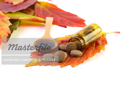 medicine bottle, pills on leaf and syrup in wooden spoon on white background