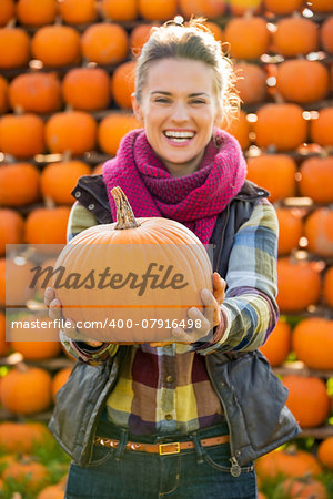 Closeup on smiling young woman holding pumpkin