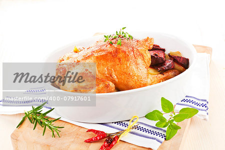 Golden grilled chicken with fresh herbs and vegetables in baking dish prepared for eating.