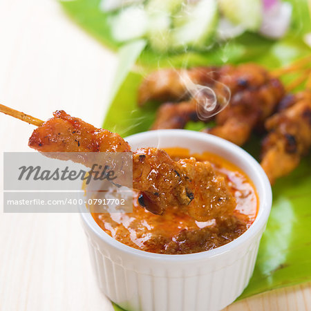 Delicious chicken sate or satay, skewered and grilled meat, served with peanut sauce. Fresh cooked with steamed and smoke. Hot and spicy Asian dish.