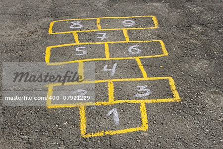 Figures in childish game hopscotch painted with yellow paint on asphalt