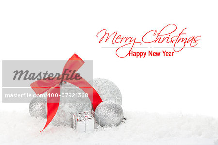 Christmas baubles and red ribbon over snow with copy space