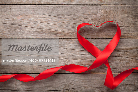 Valentines day heart shaped red ribbon over wooden table background with copy space