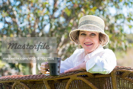 Smiling woman sitting  in the garden  and holding a  cup