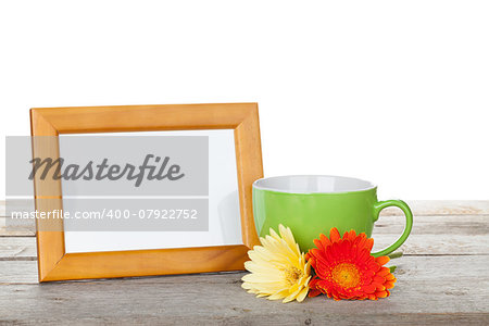 Photo frame on wooden table with cup of coffee and gerbera flowers