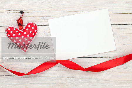 Photo frame or greeting card with valentines toy heart over wooden table background